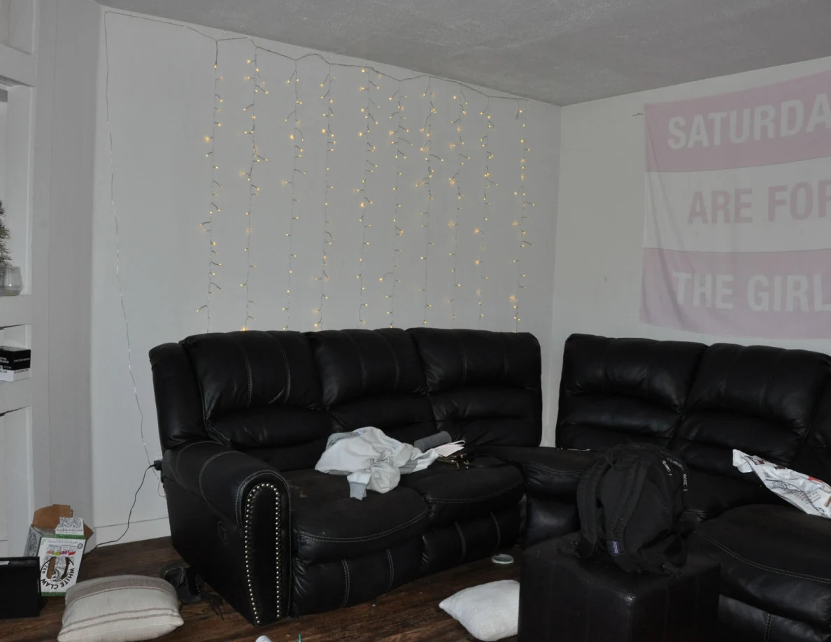 Black sofas beneath string lights and a pink banner, with a backpack and cushions nearby.