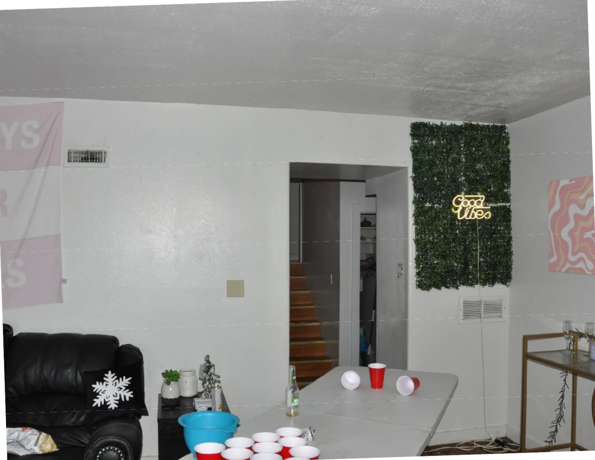 Folding table with cups beside a green wall panel and illuminated Good Vibes sign.
