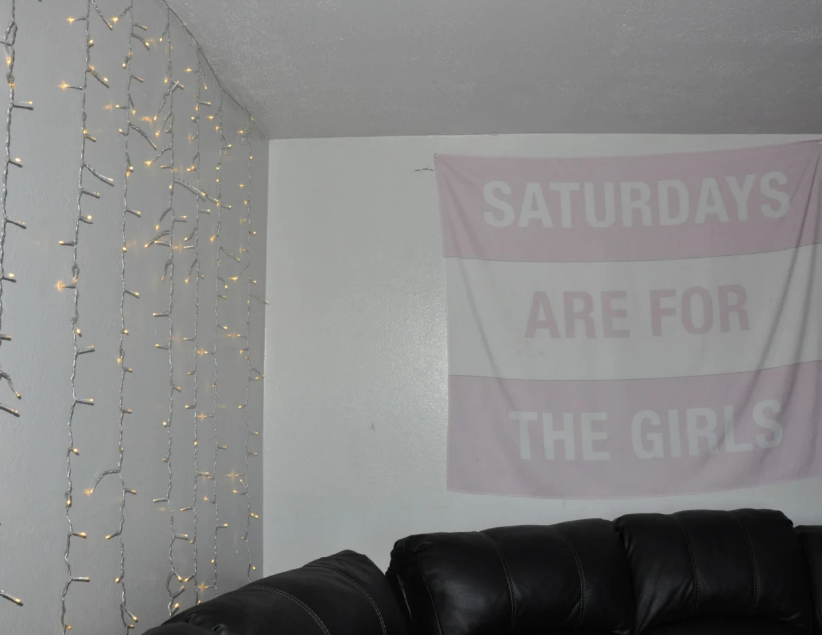 String lights and a pink Saturdays Are For The Girls banner above black seating.