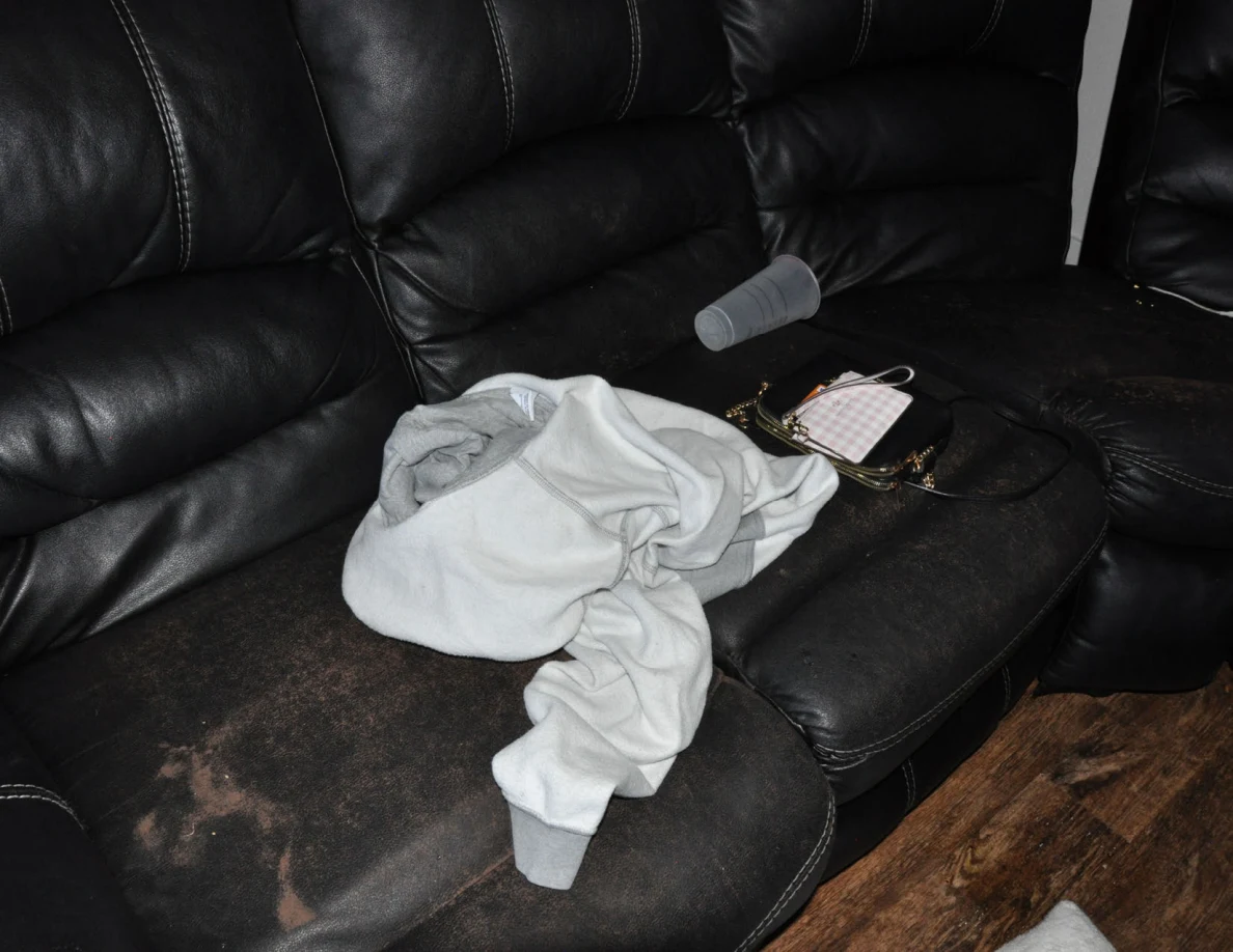 Black sofa cushions with pale fabric, clear cup and a small purse.