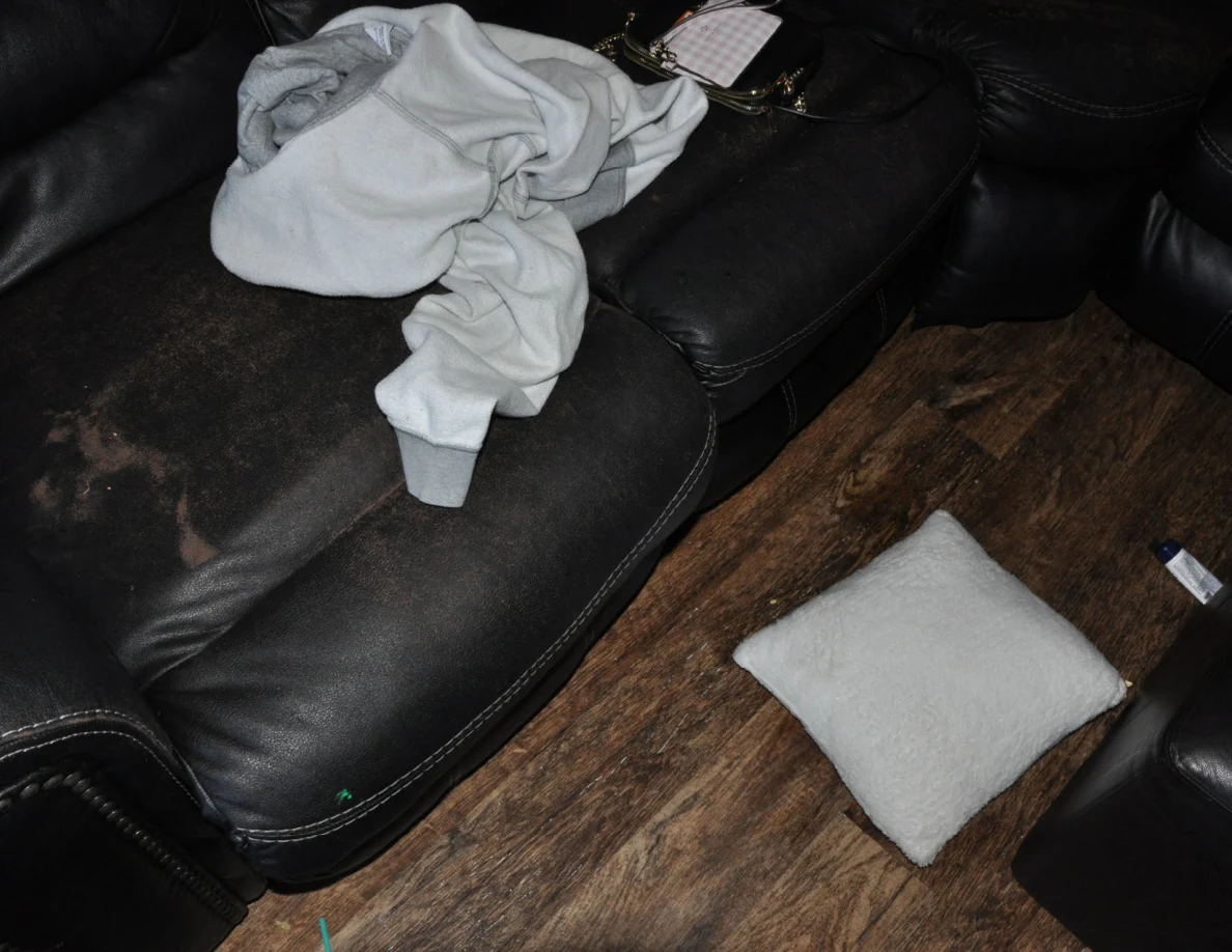 Pale fabric on a worn black sofa above a white cushion on the floor.