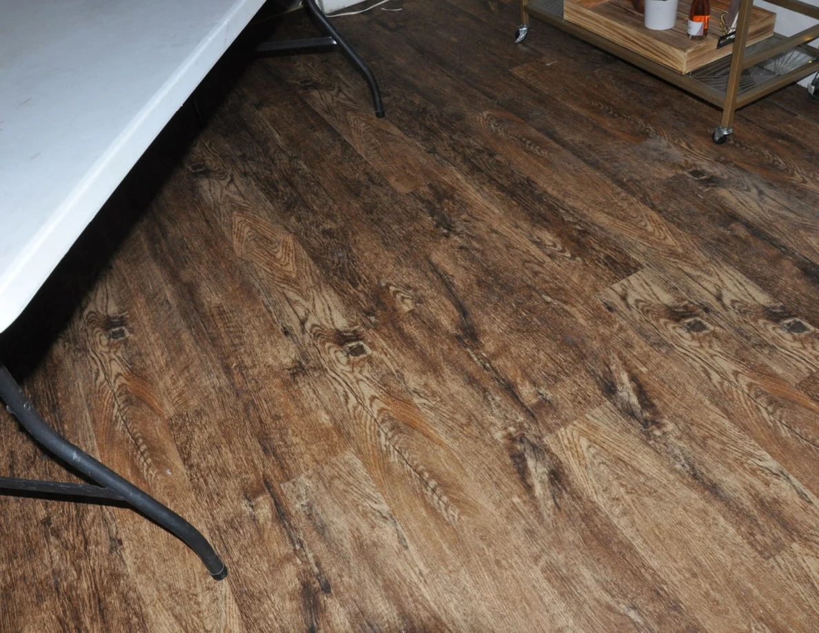 Wood-look flooring beneath the edge of a folding table and drinks cart.