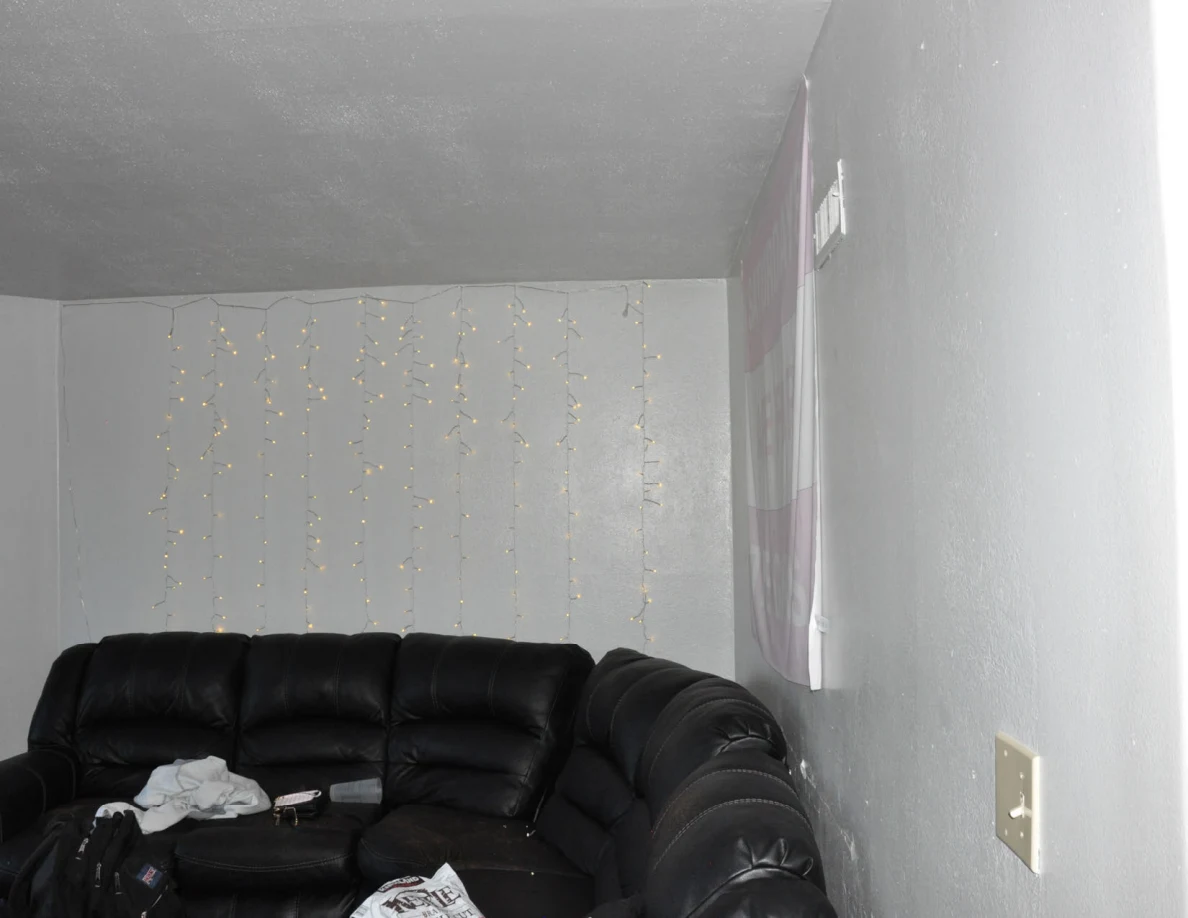 Upper view of black sectional sofa and string lights against white walls.