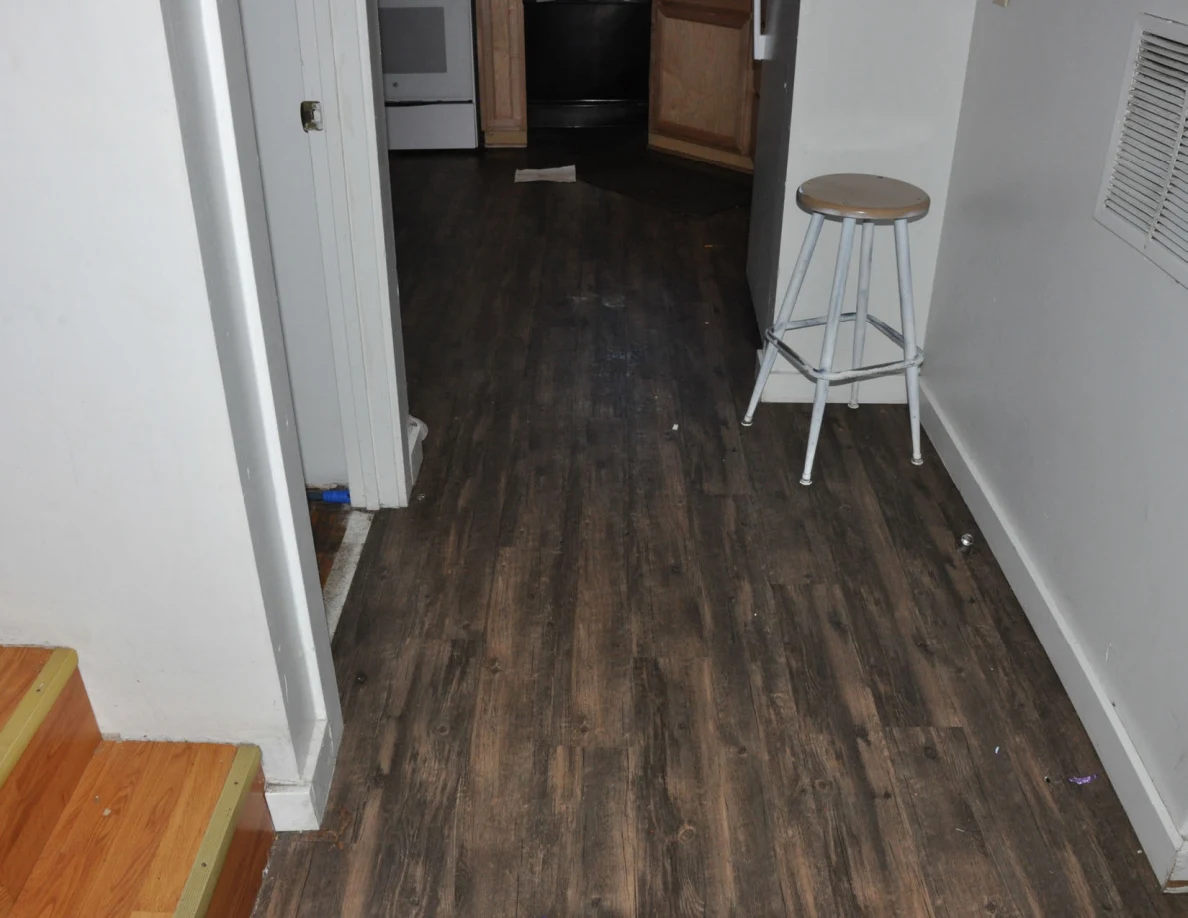 Hallway with wood-look flooring and a tall stool leading toward the kitchen.