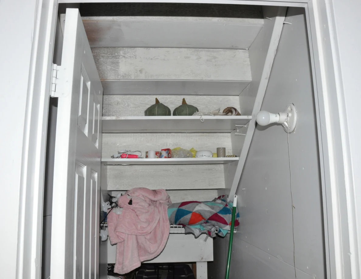Closet shelves with household containers, decorative objects and piled linens.