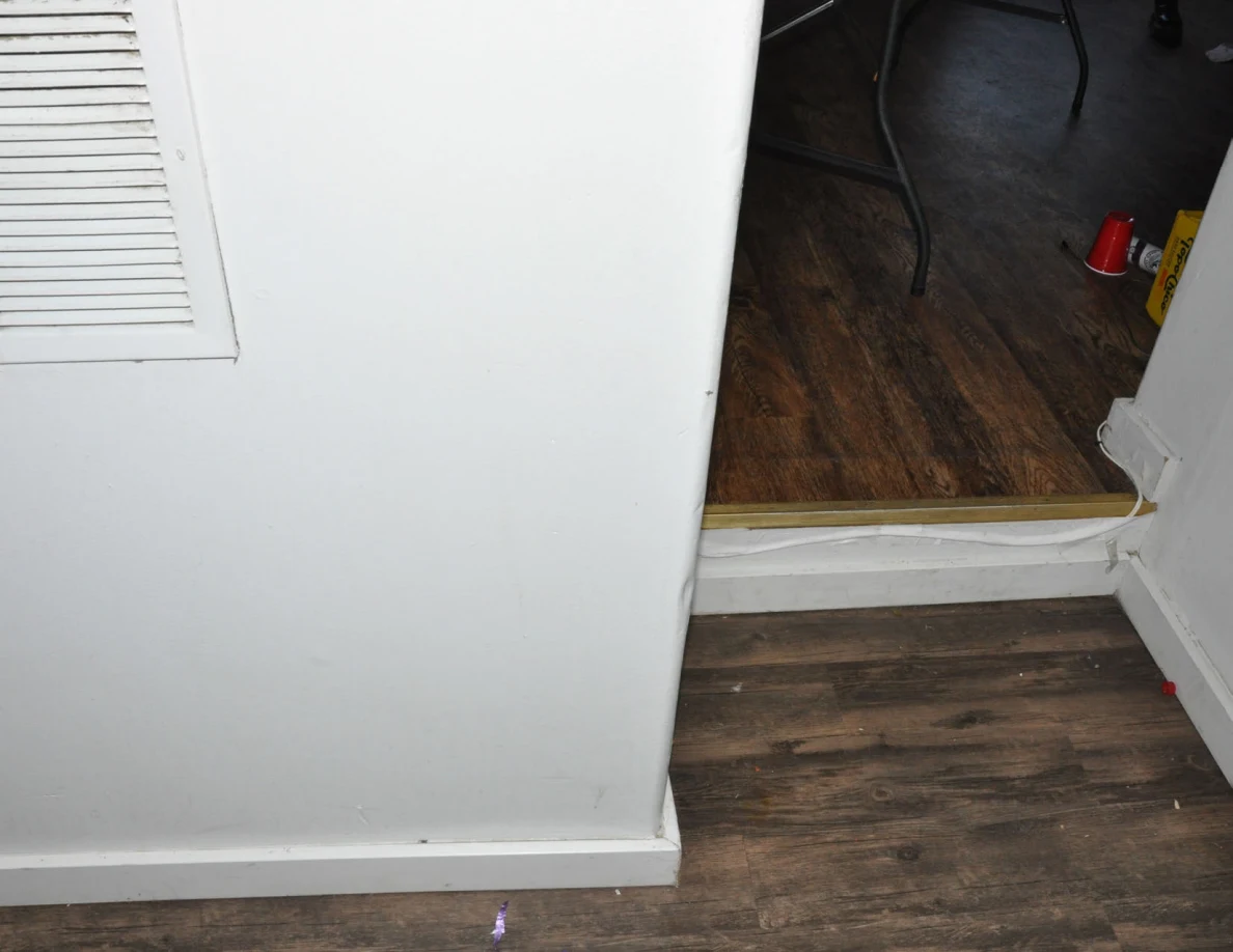White wall vent beside a doorway step leading into the living room.