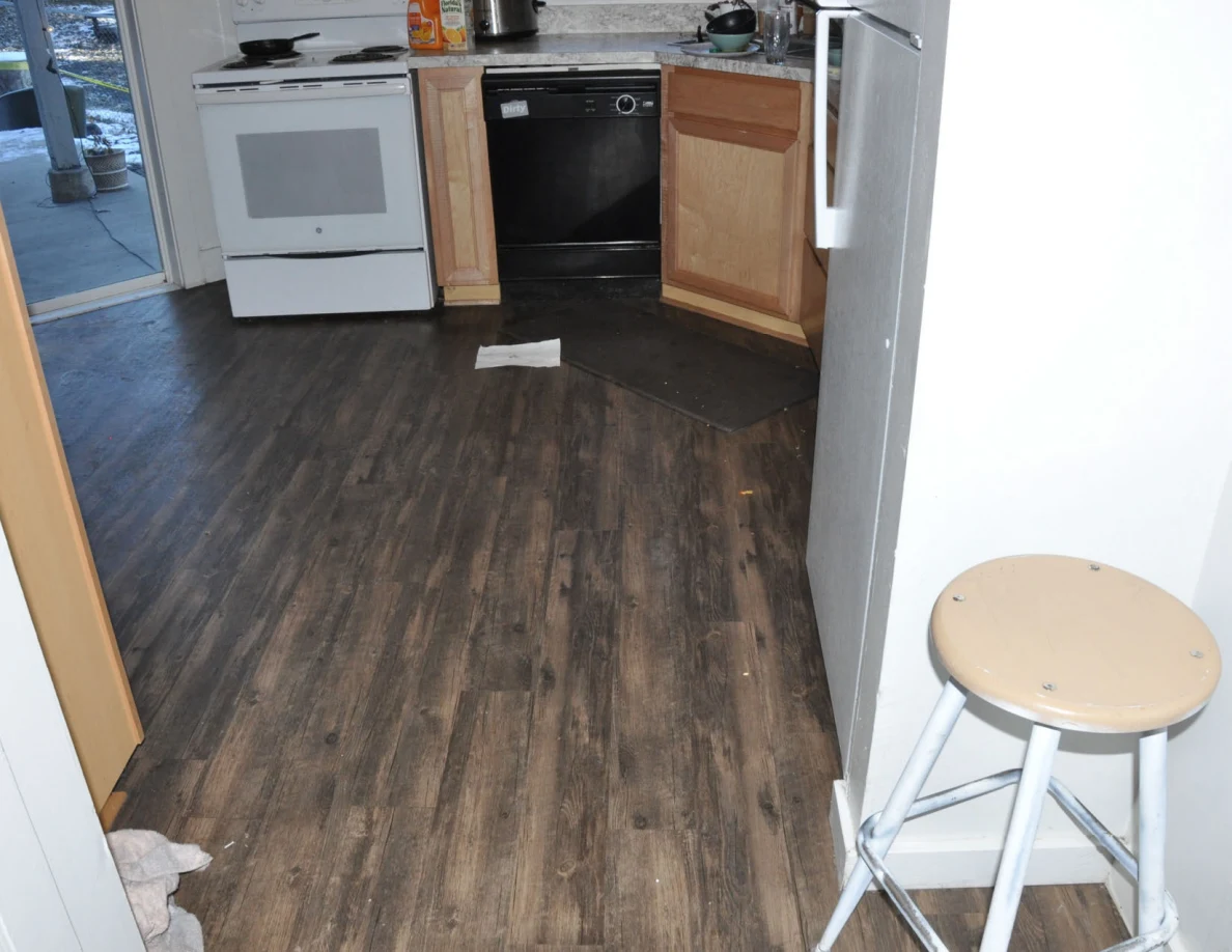Hallway stool beside kitchen entrance showing a stove, dishwasher and open cabinet door.