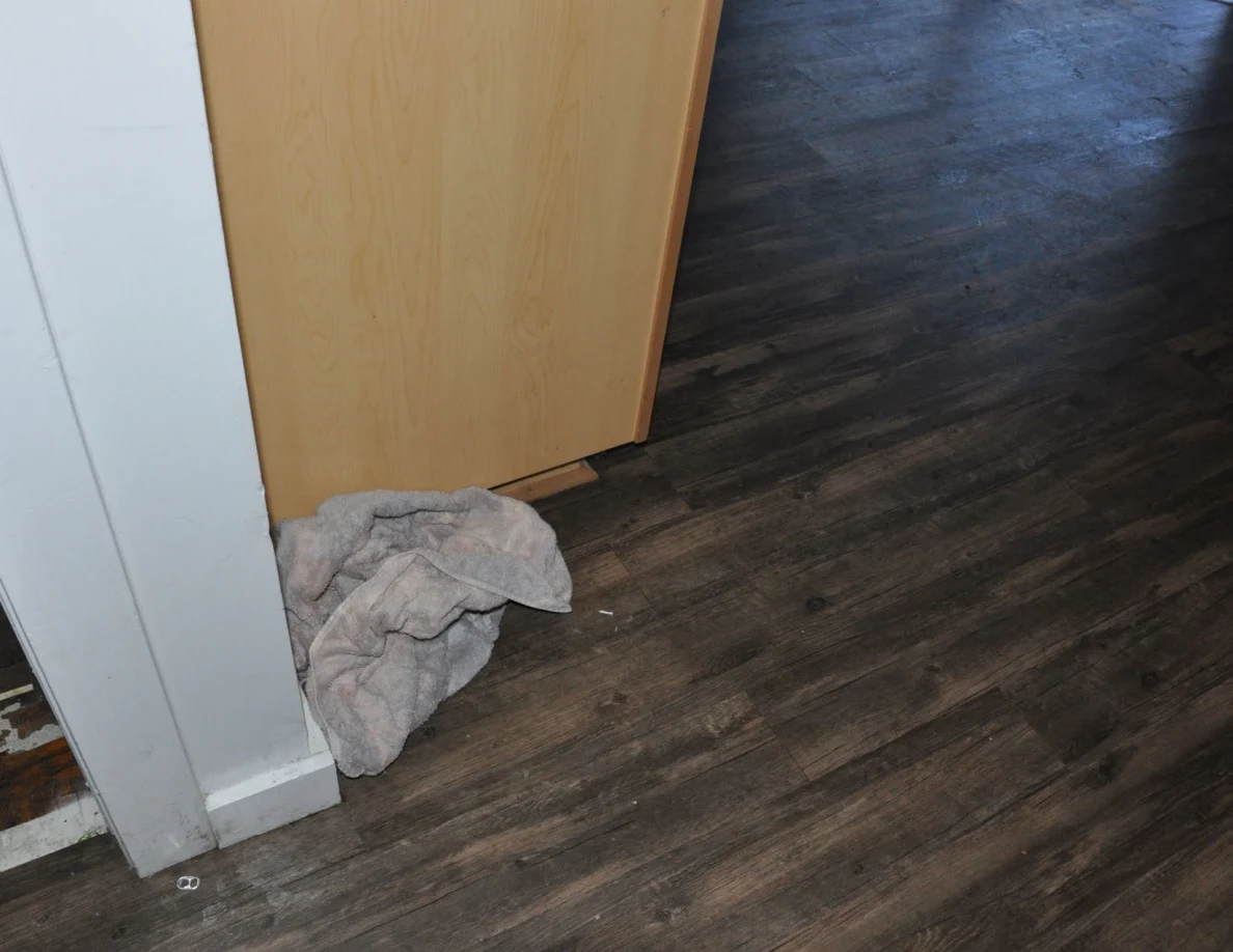 Crumpled gray cloth on the floor beside the base of a wooden door.