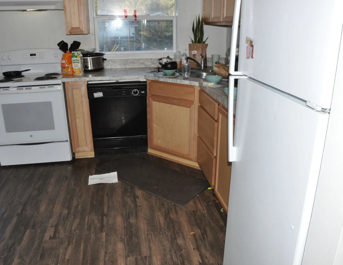 Kitchen appliances and corner sink cabinet with one lower door open.