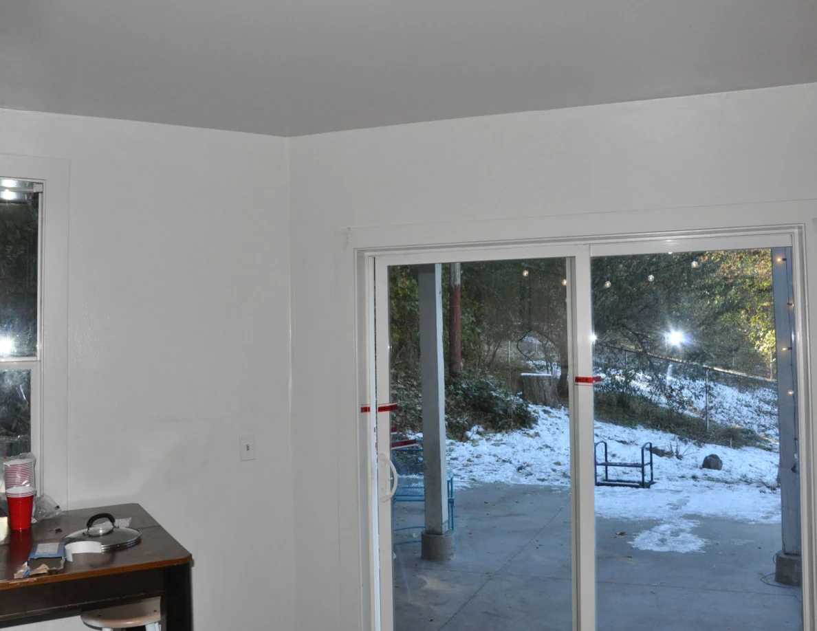 Sliding glass door with red tape across its frame, overlooking a snowy patio.
