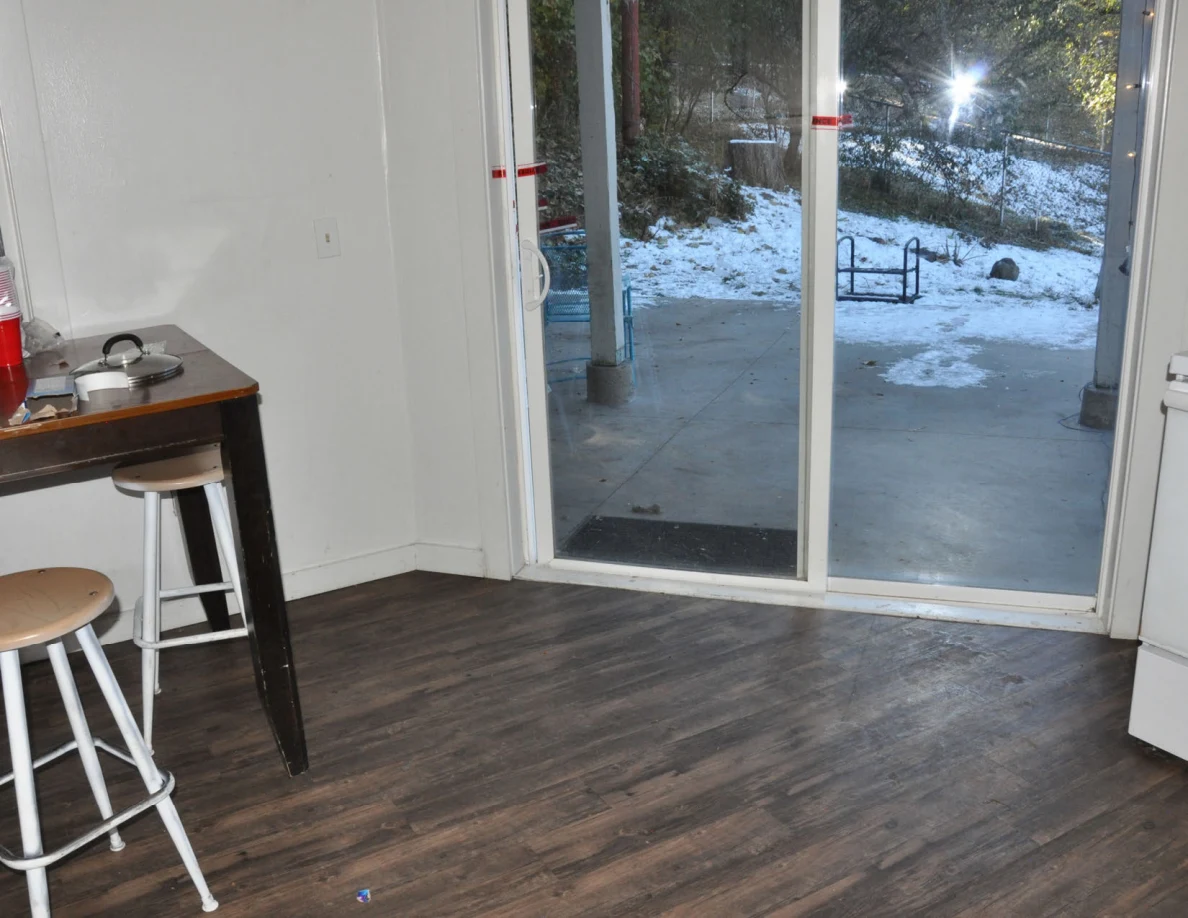 Kitchen floor and stools beside a sliding glass door overlooking snow.