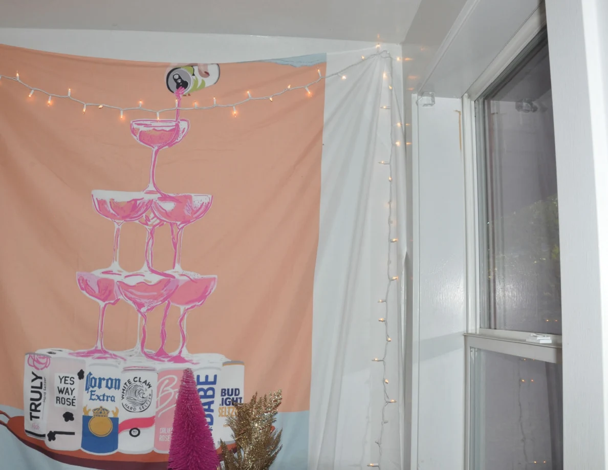 Drinks-themed wall hanging with string lights beside a kitchen window.