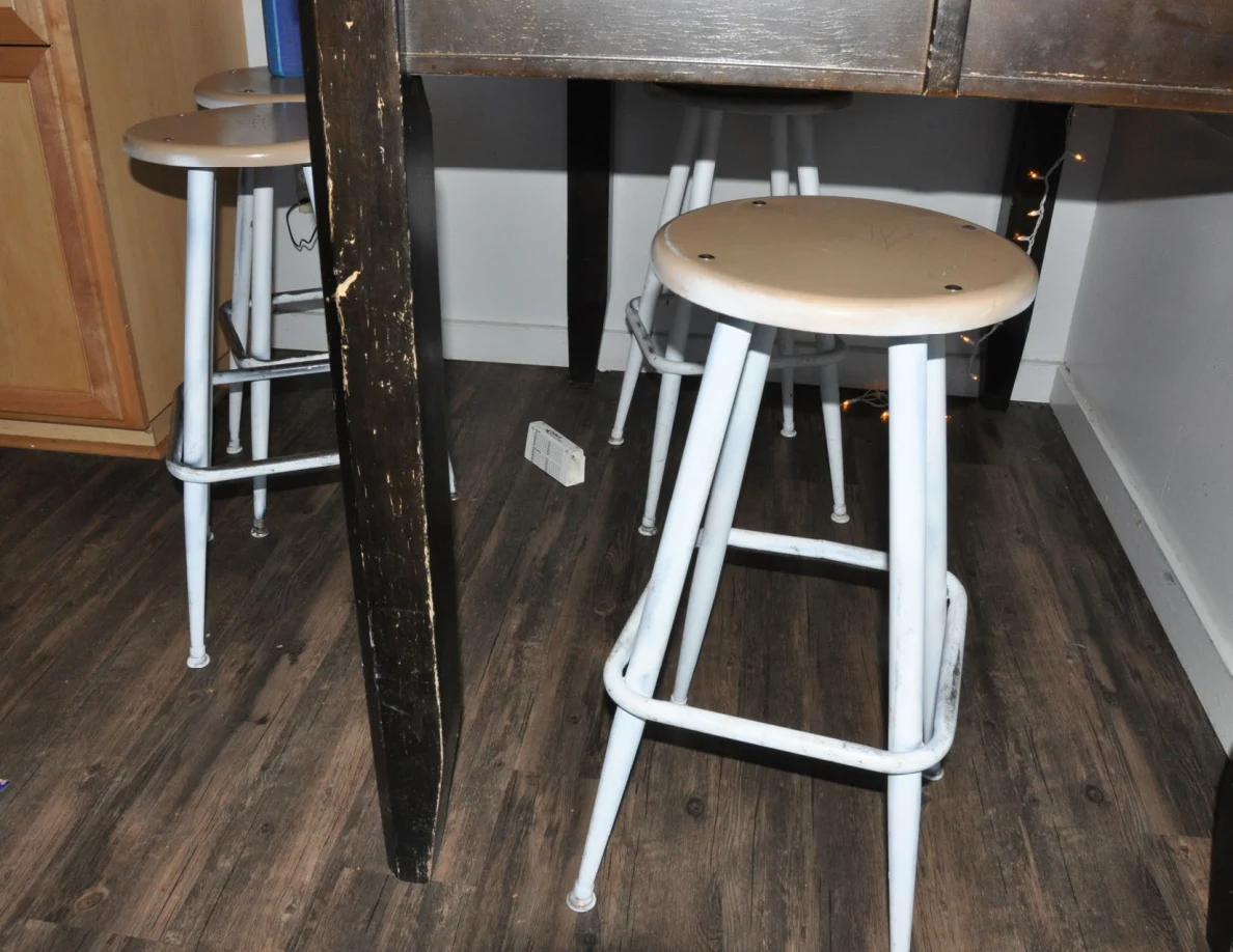 White metal stools beneath a dark wooden kitchen table.