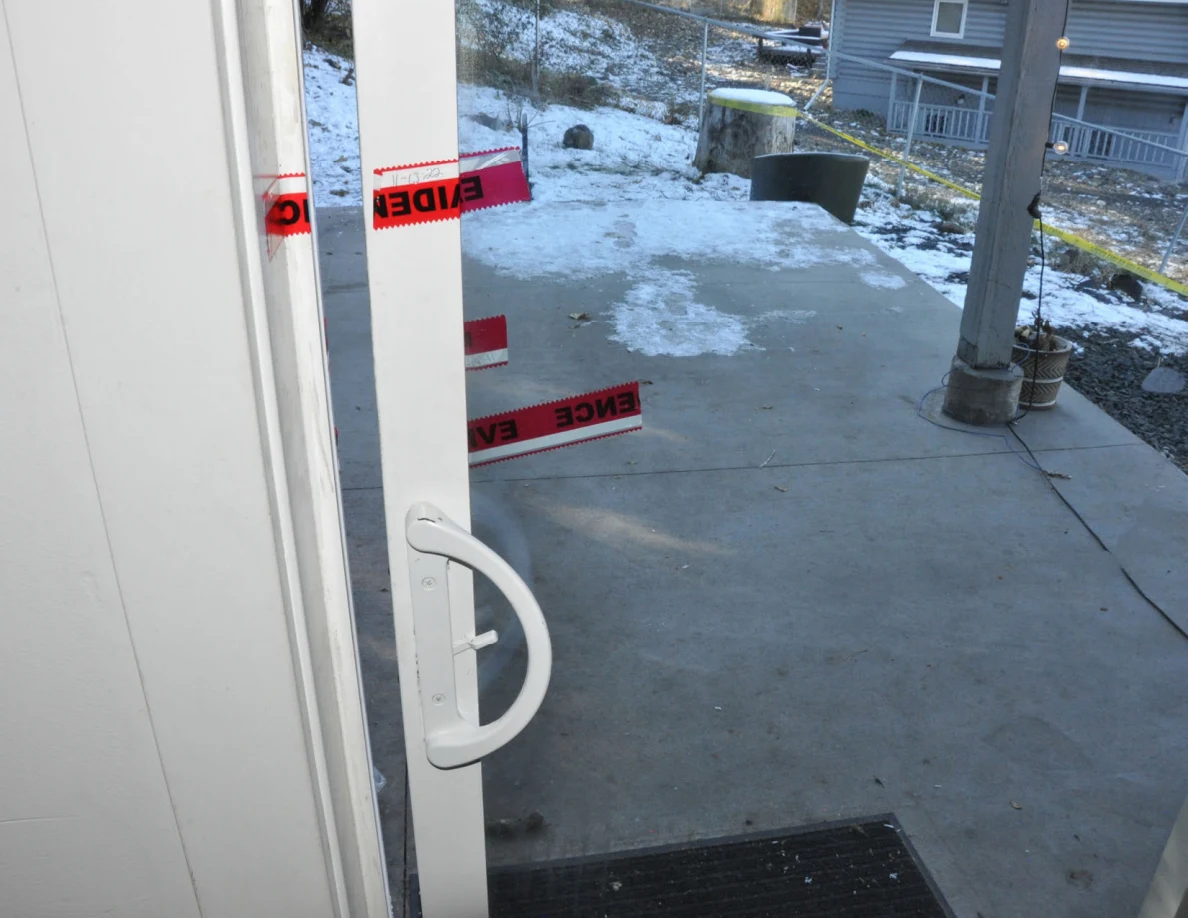 Sliding-glass door handle and red evidence tape, with a snowy patio beyond.