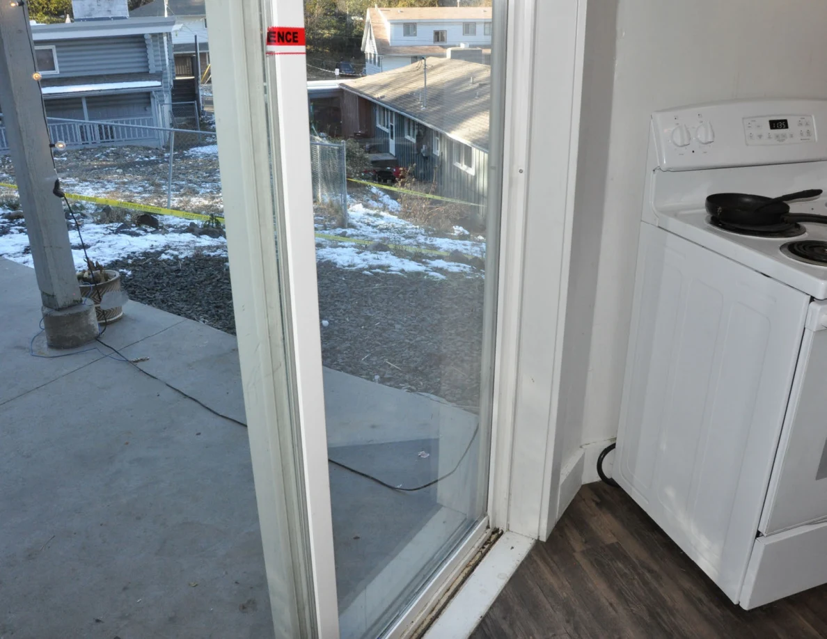 Lower sliding door and track beside a white kitchen stove.