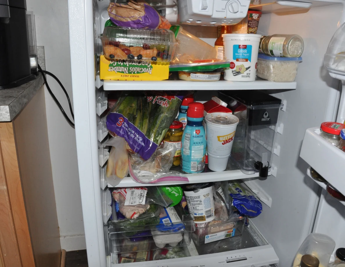 Refrigerator interior with produce, takeaway cups, food tubs and packaged groceries.