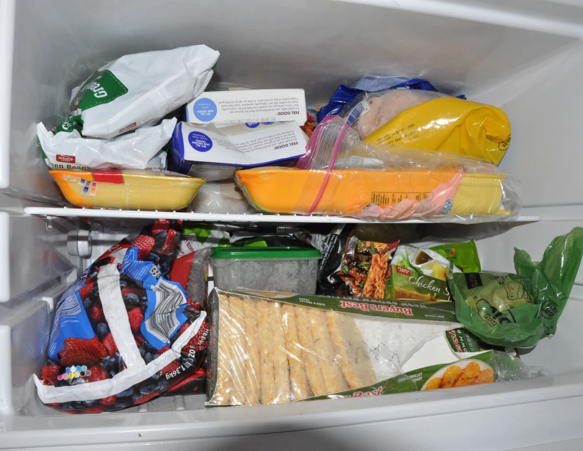 Close view of freezer shelves crowded with frozen-food packages and bags.