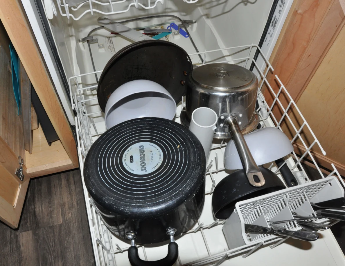 Lower dishwasher rack loaded with pots, pans, bowls and utensils.