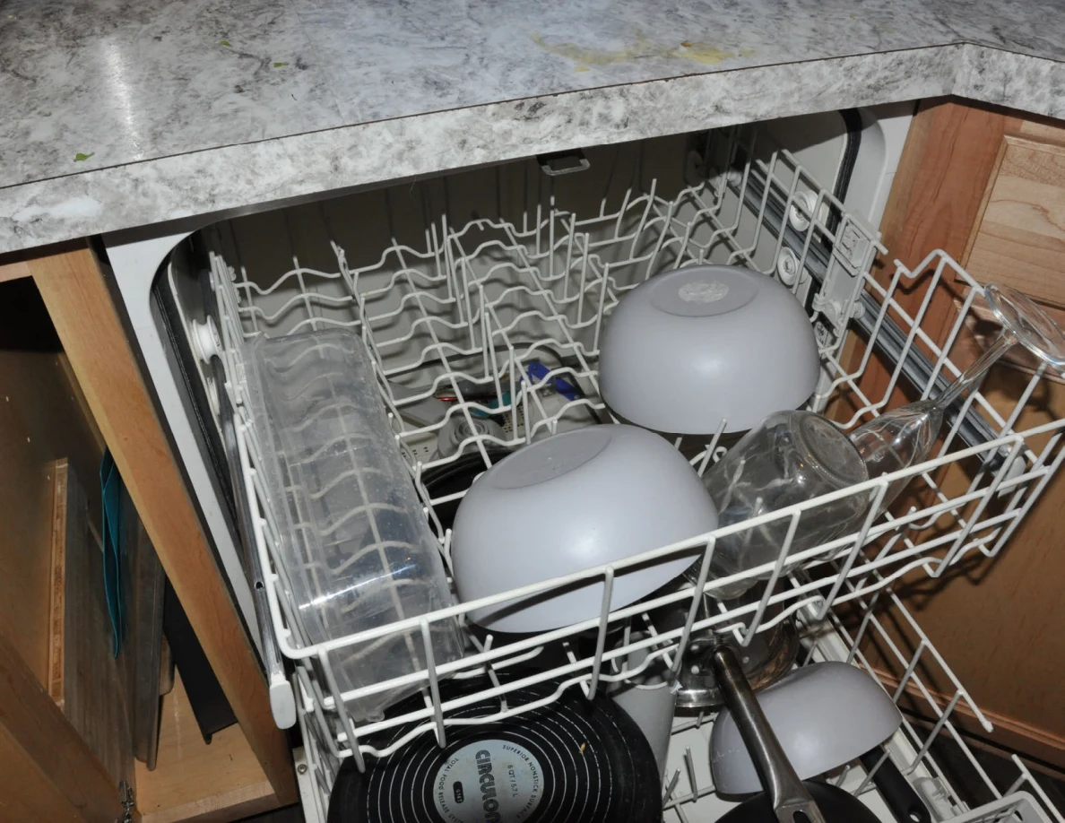 Upper dishwasher rack with bowls, glasses and plastic containers.