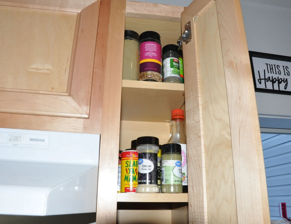 Upper spice cabinet shelves containing jars and condiment bottles.