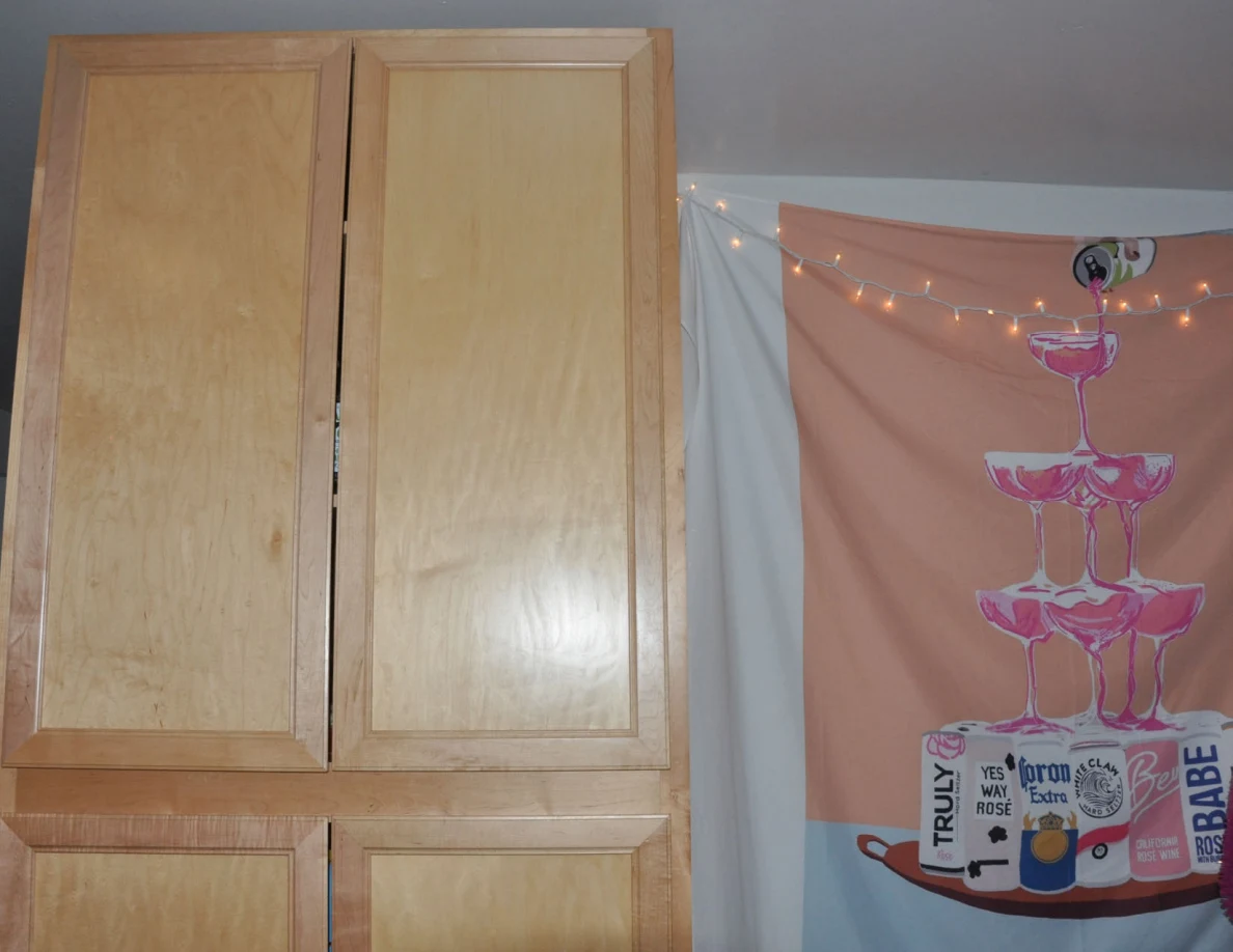 Upper pantry doors beside a drinks-themed wall hanging and string lights.