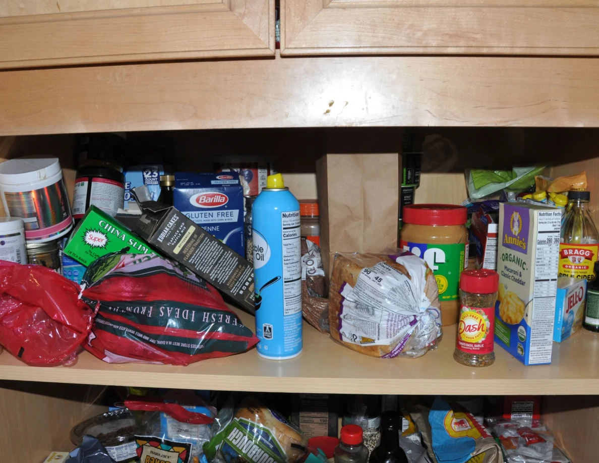 Pantry shelf with boxed pasta, cooking spray, jars and seasoning containers.