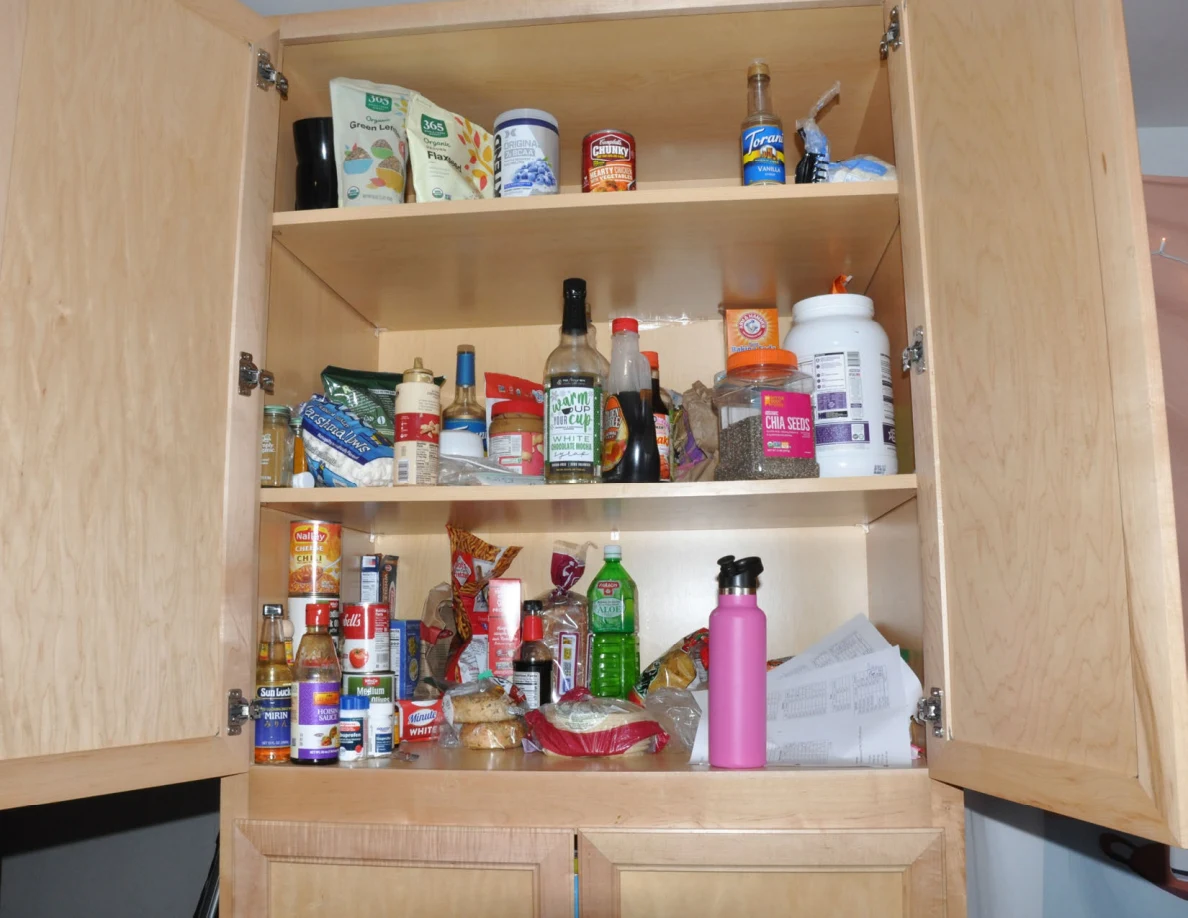 Open upper pantry with shelves of jars, bottles, packets and canned food.