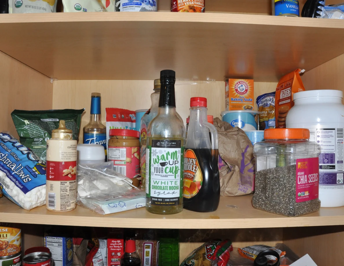 Pantry shelf with cooking oil, sauces, chia seeds, baking supplies and other groceries.