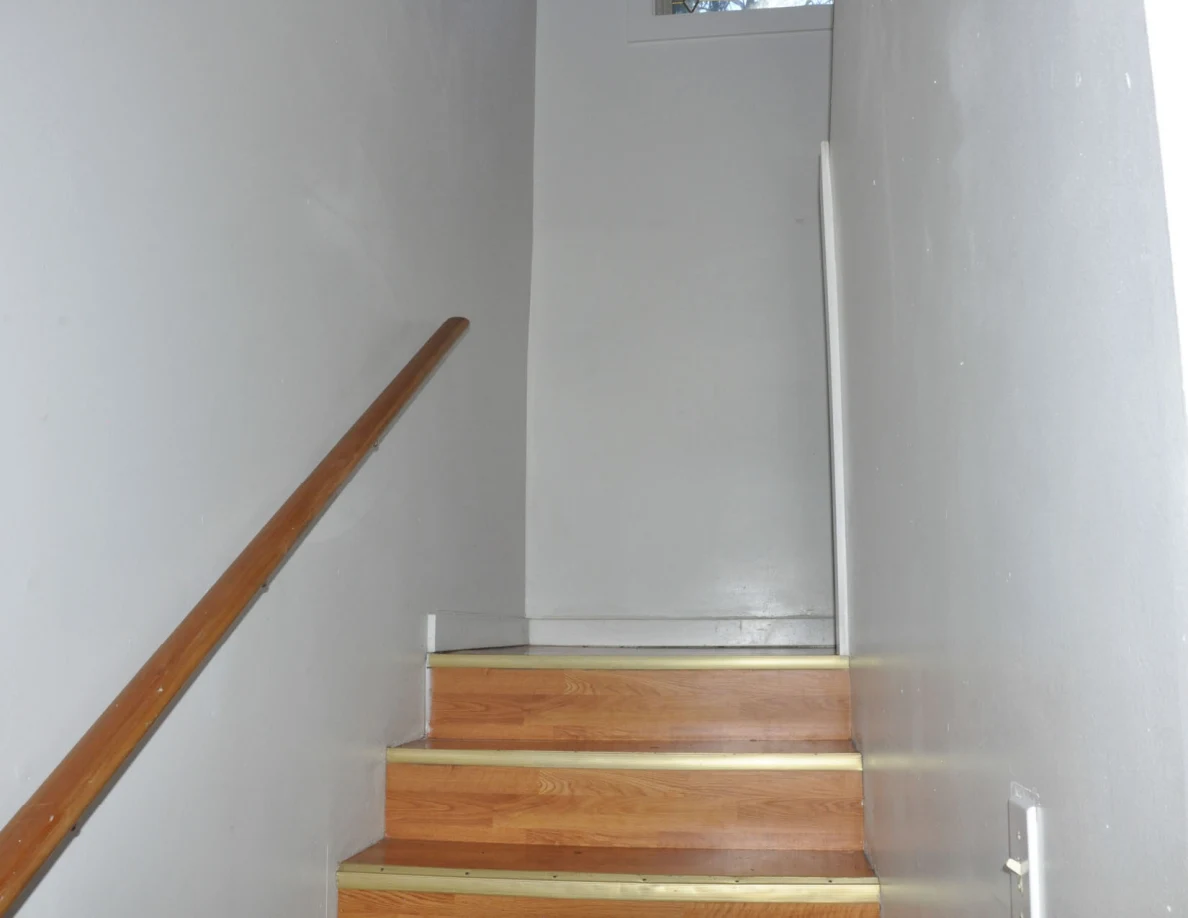 Upper staircase and white wall below a high window.