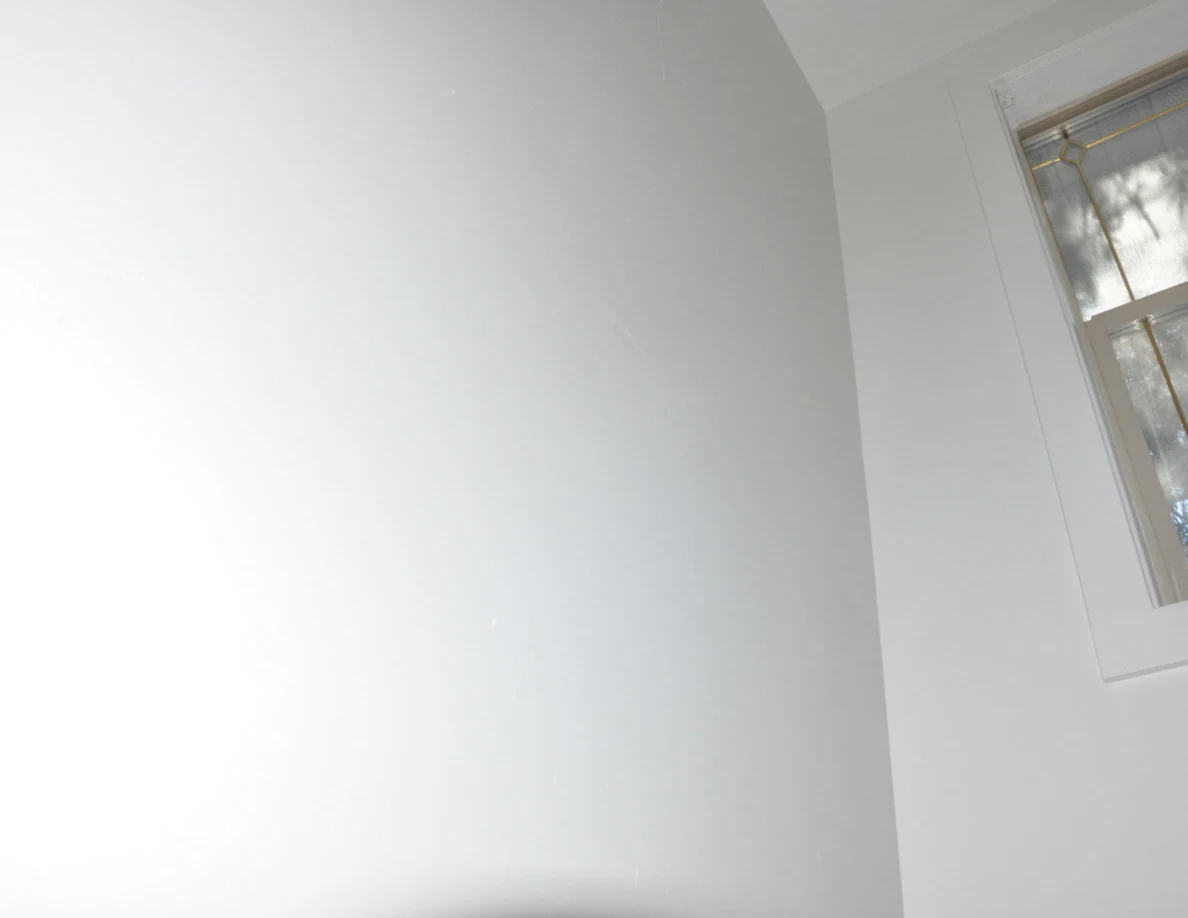 Upper white stairwell wall beside part of a window.