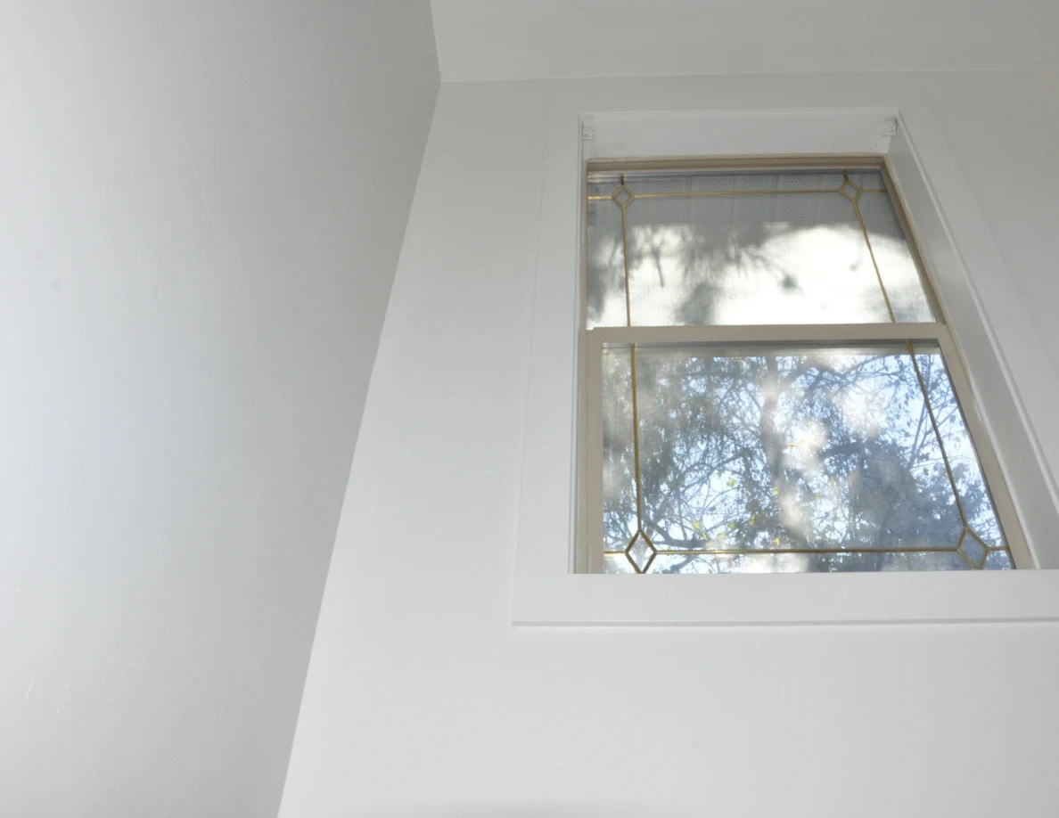 Stairwell window with decorative border and trees visible through the glass.