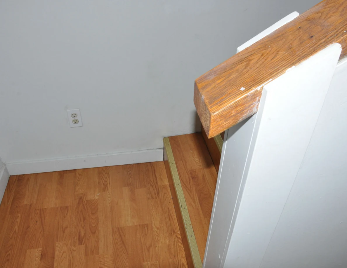 Wooden landing beside a half-wall with a broad wooden cap and electrical outlet.