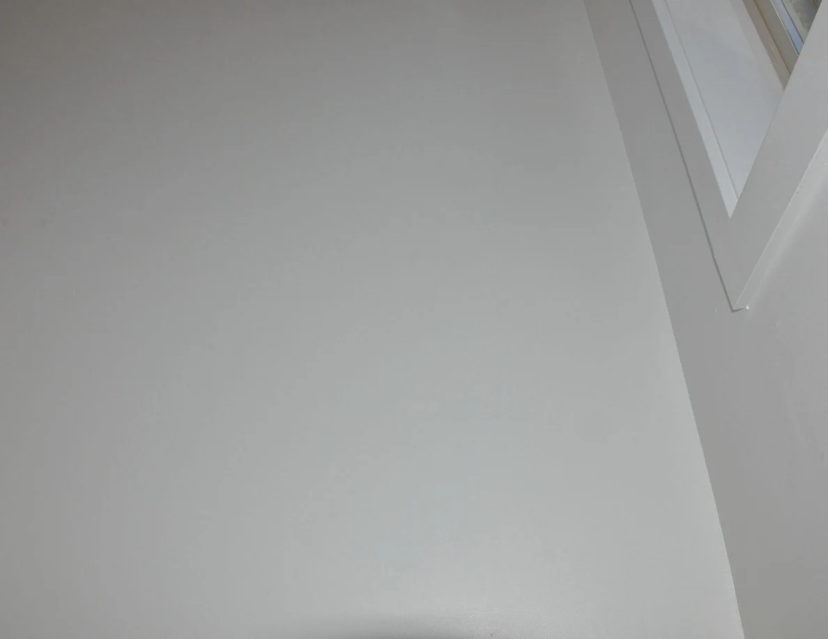 Upper white stairwell wall beside window trim.