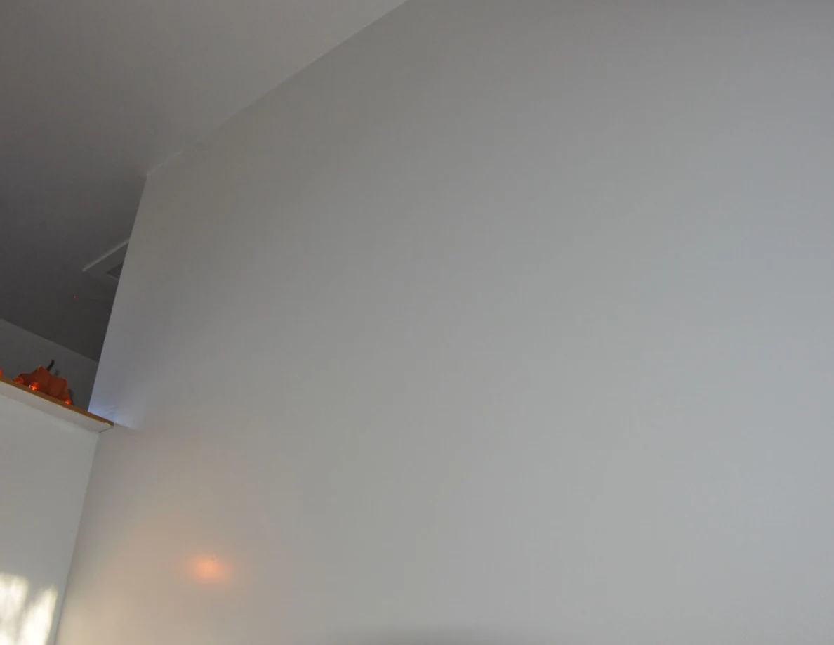 Tall white wall and ceiling corner above a decorated stair ledge.