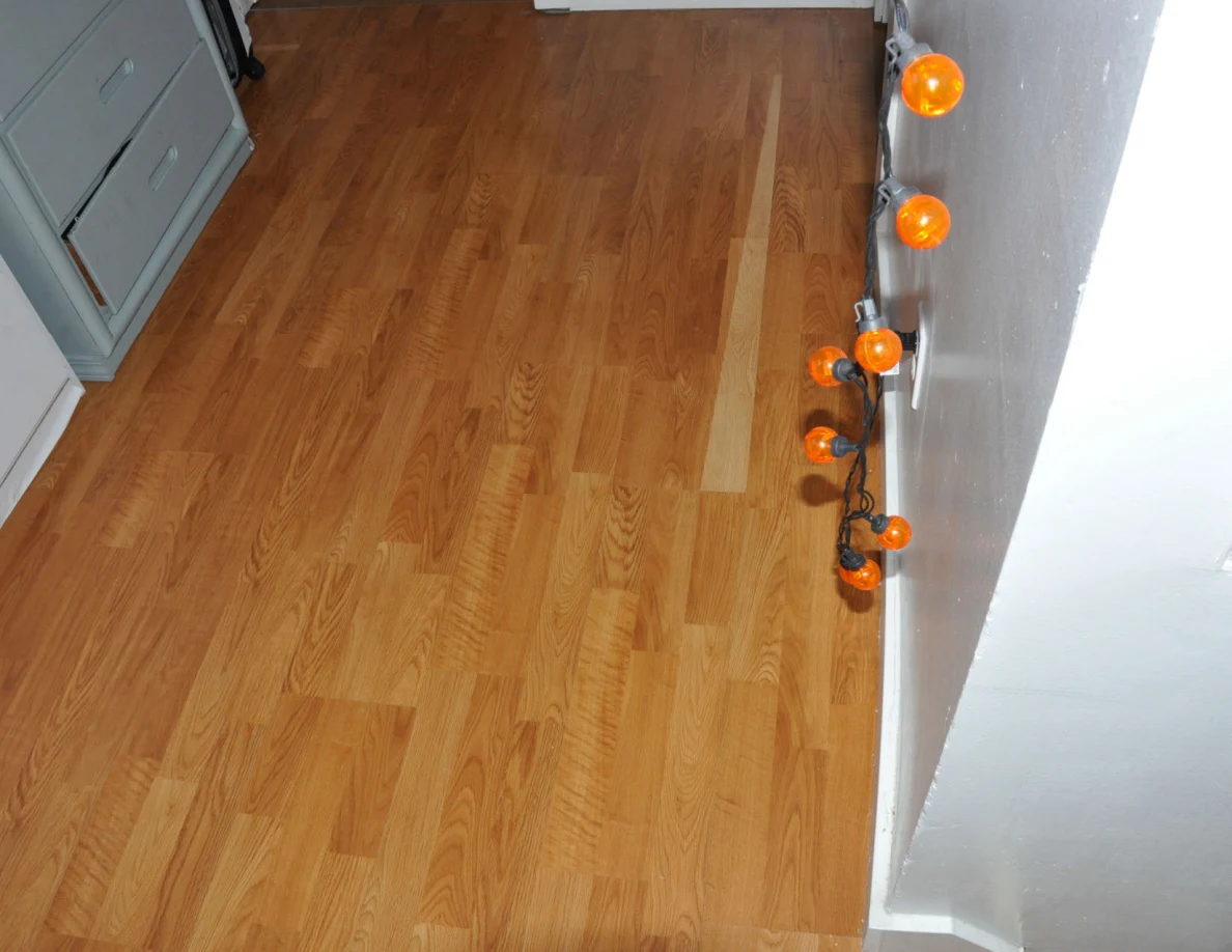Wooden landing floor beside drawers and orange pumpkin-shaped string lights.