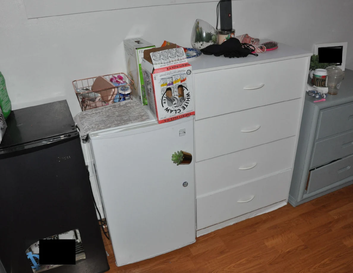 Compact refrigerators beside white drawers, topped with drink cartons and personal items.
