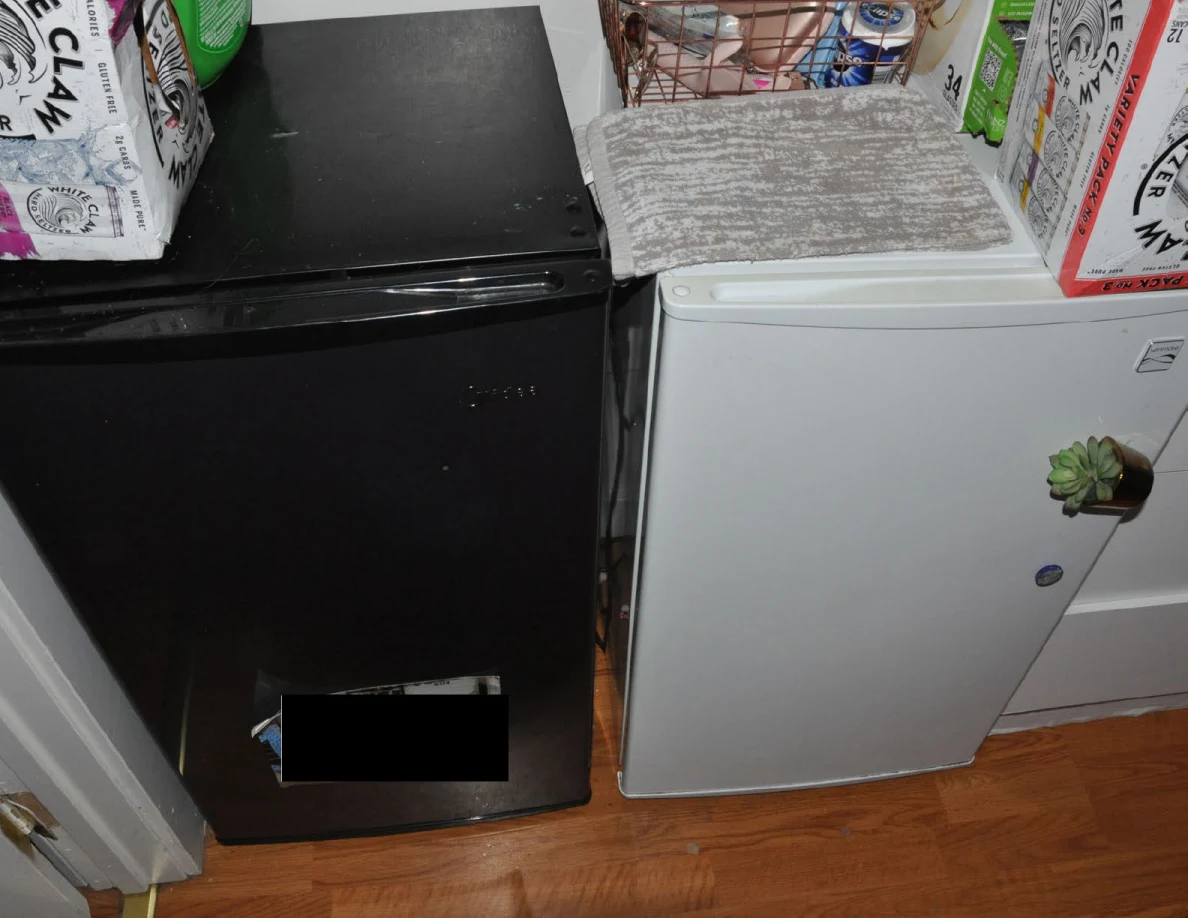 Closed black and white compact refrigerators with cartons and a folded cloth on top.