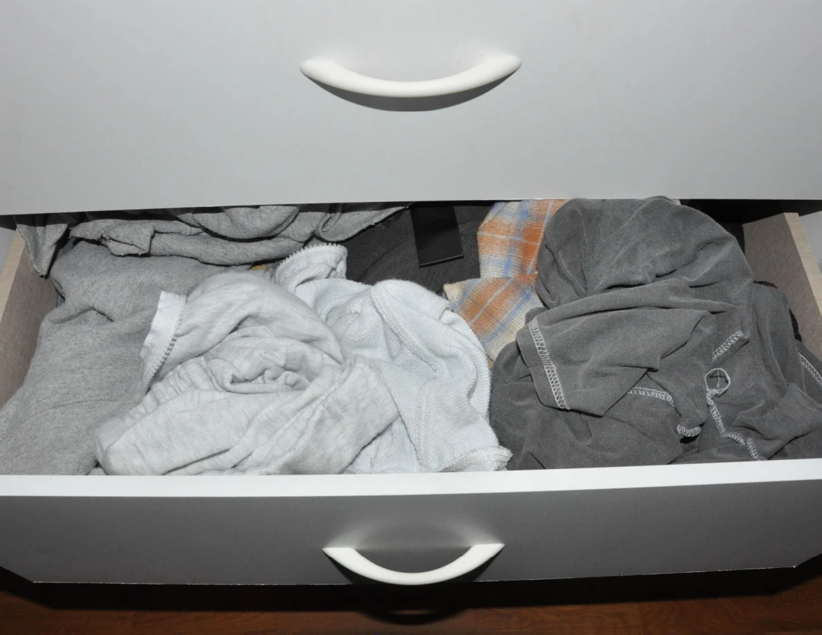 Open drawer containing pale and dark folded clothing.
