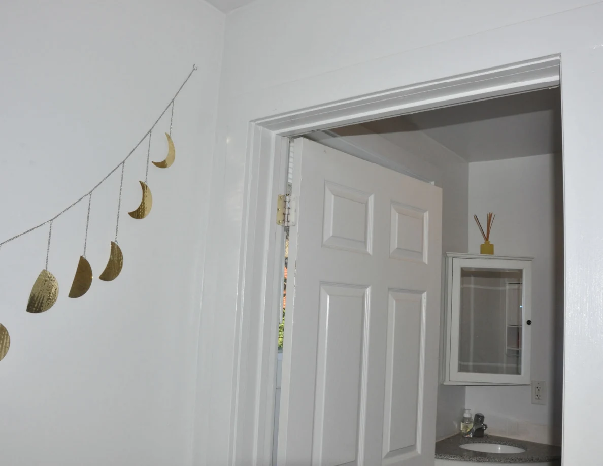 Moon-phase wall garland beside an open bathroom doorway.