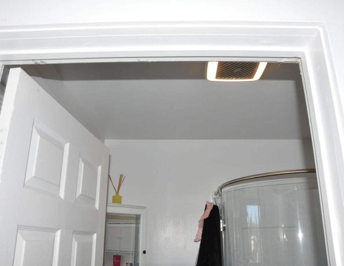 Upper bathroom doorway with ceiling vent and curved shower enclosure.
