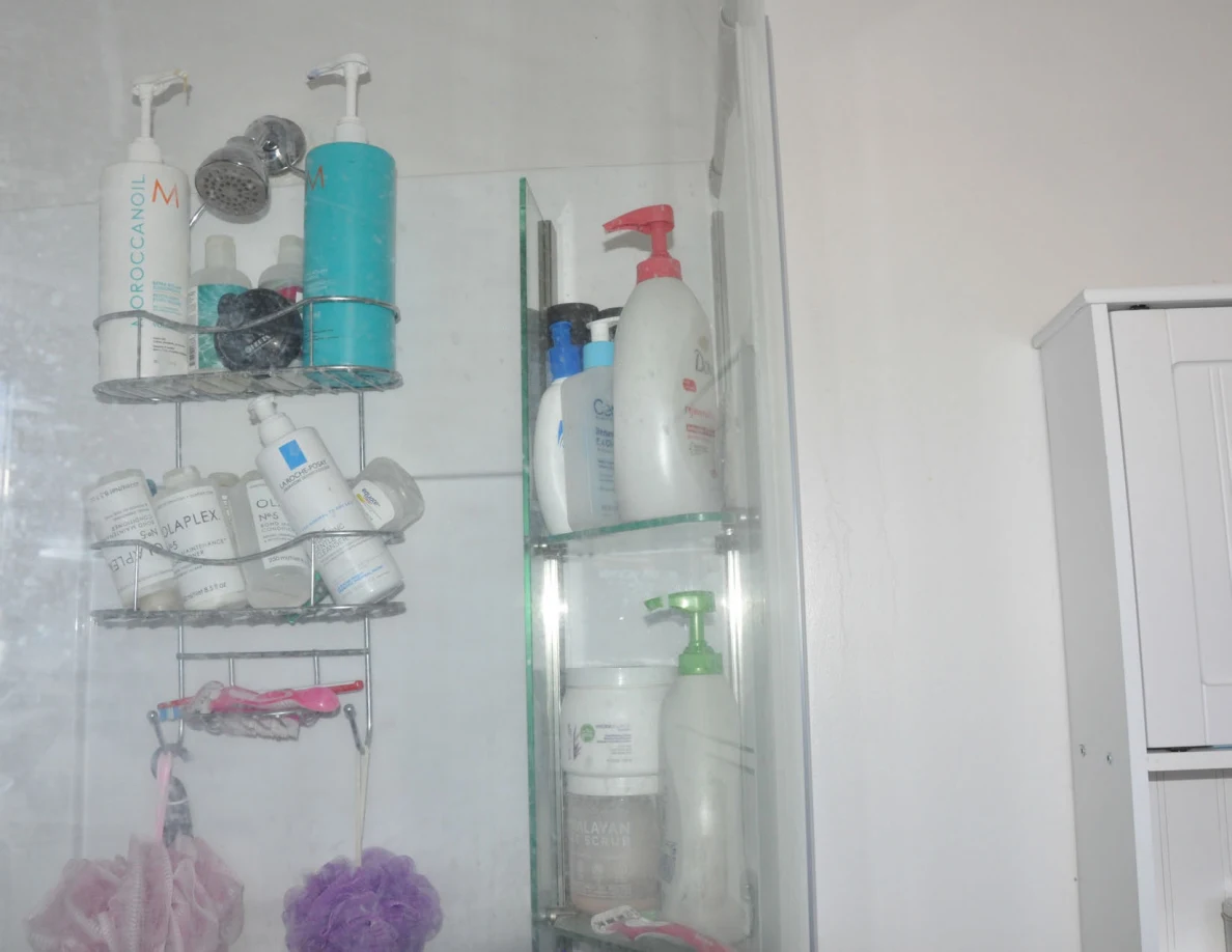 Shower caddies holding shampoo and toiletry bottles with hanging bath poufs.