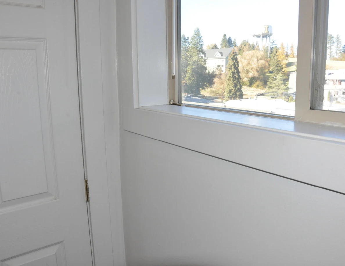 Lower bathroom window and wall beside a white door.