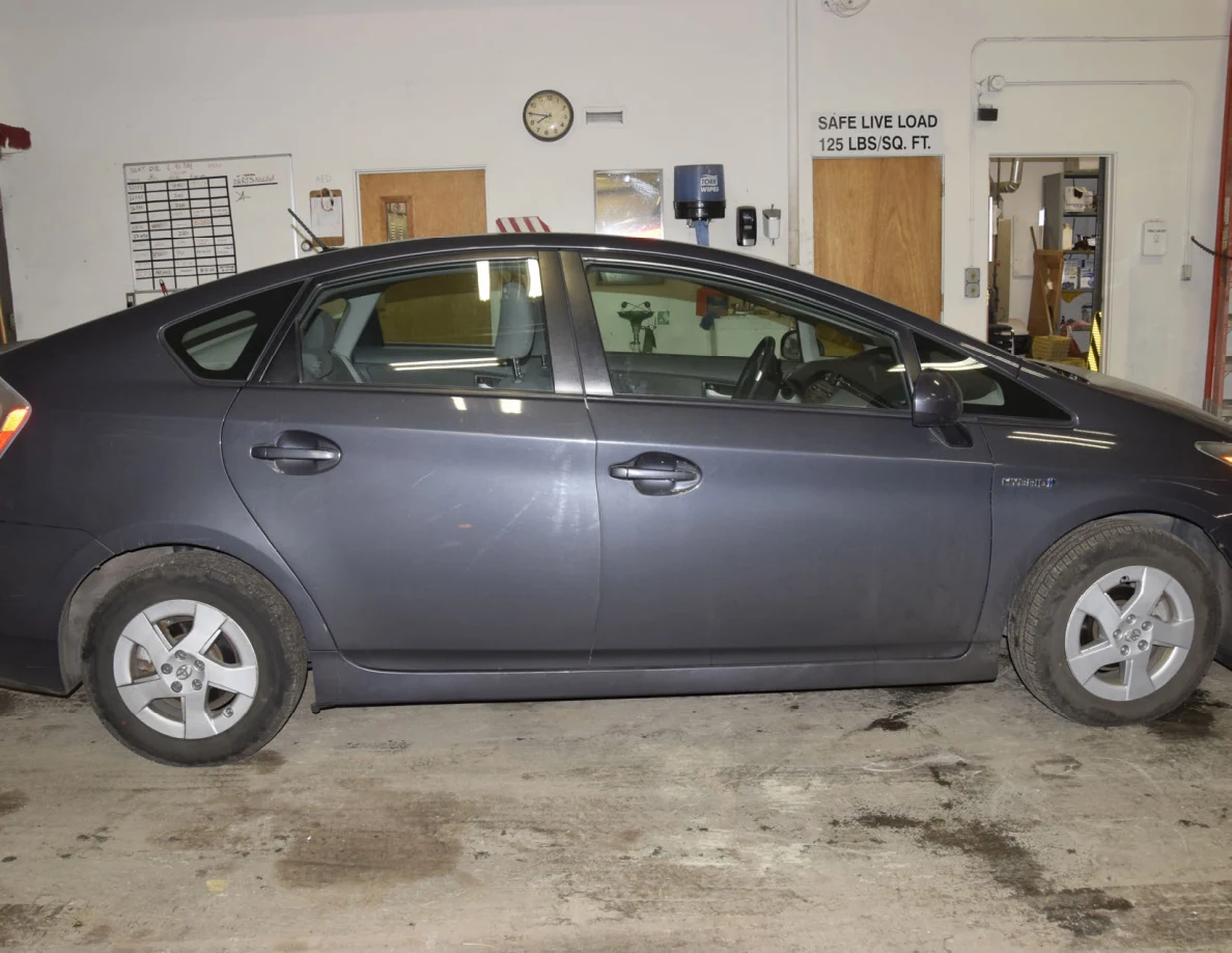 Side view of a dark blue hatchback showing both doors and wheels inside a garage.