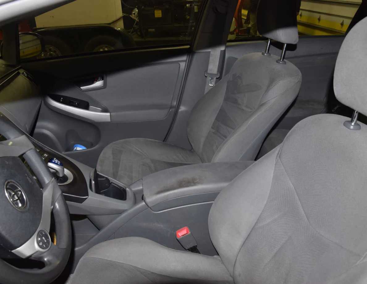 Gray fabric front seats with center armrest, gear selector and seat-belt buckles.