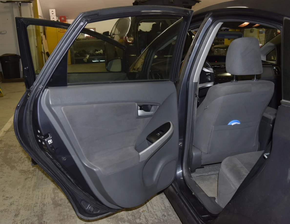 Open rear door showing gray door trim and the back of a front seat.