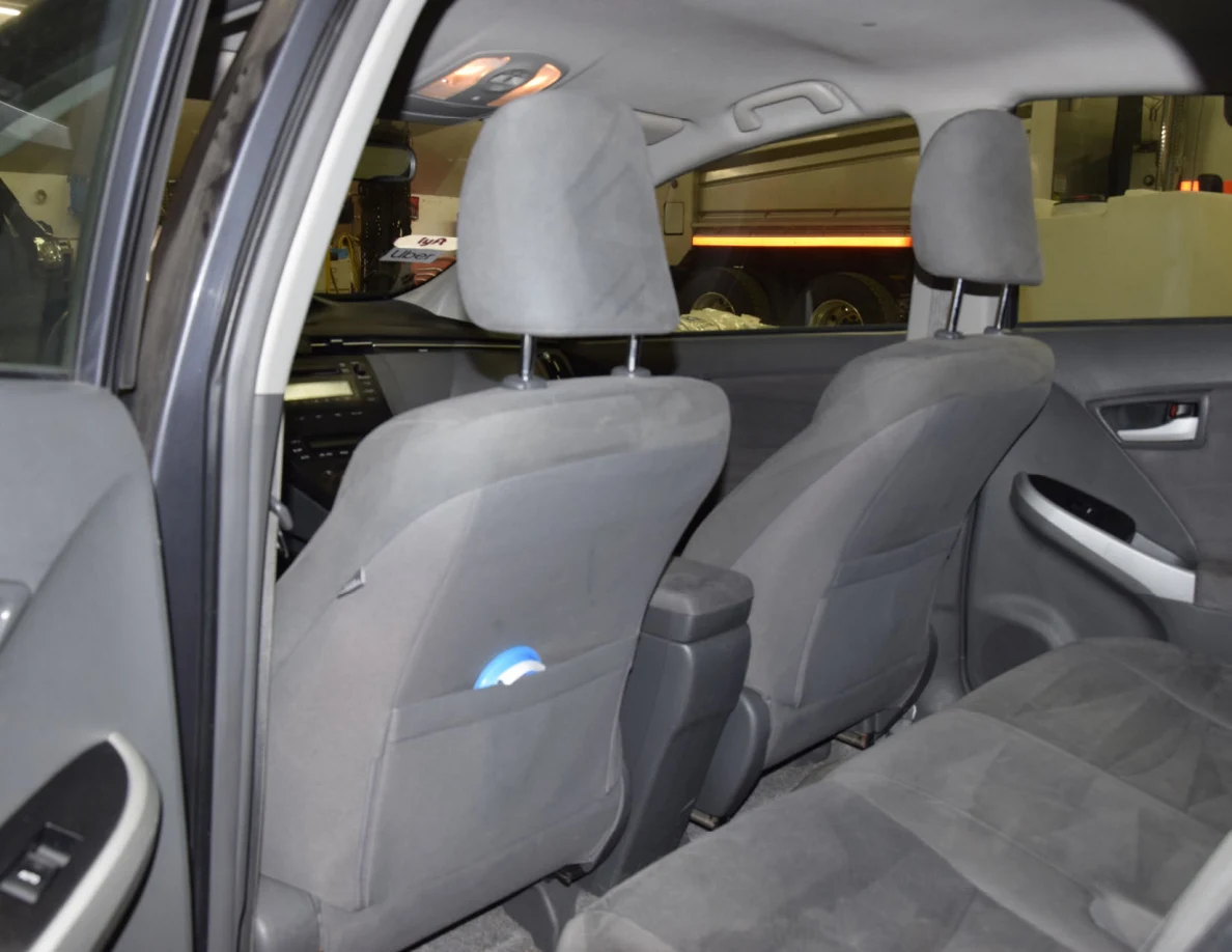 Rear seating area with gray upholstery and a blue object in a front-seat pocket.