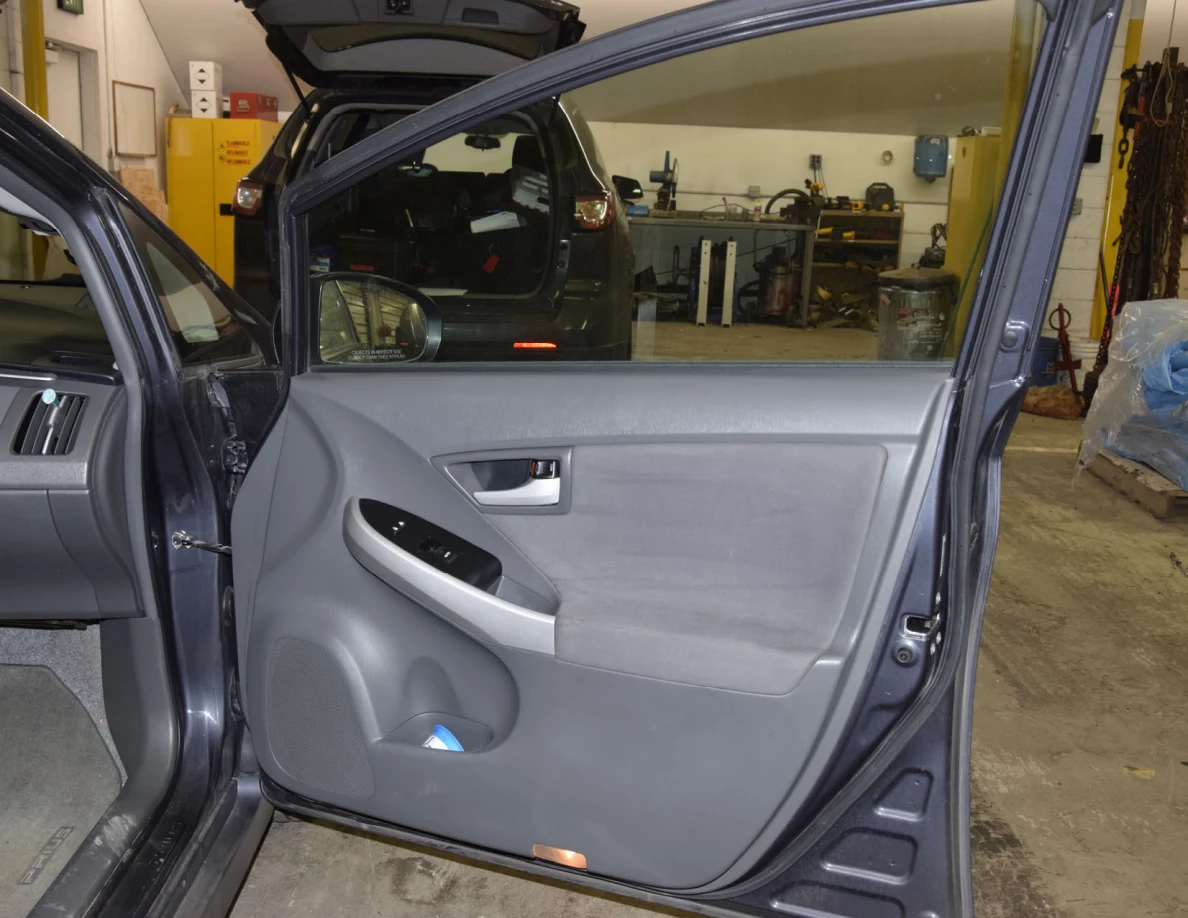 Open front passenger door with gray trim, silver handle and a blue container in the lower pocket.