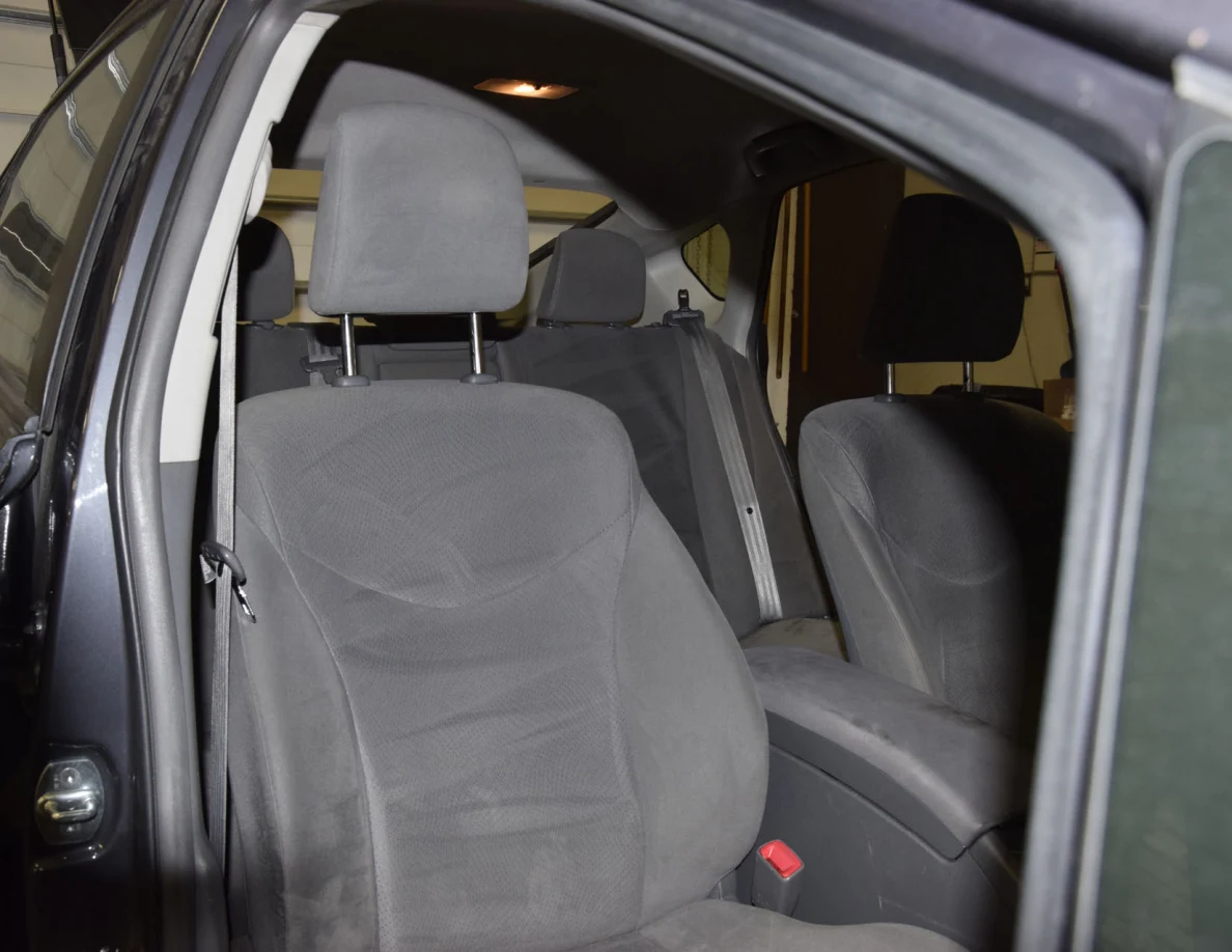 Gray fabric front passenger seat and headrest viewed through an open door.