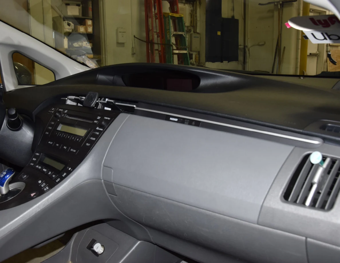 Passenger dashboard, glove compartment and audio controls in a gray car interior.