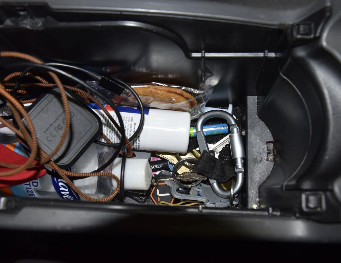 Center-console storage with keys, carabiner, cords, charging adapters and small containers.